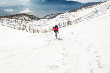 Fototapeta na wymiar Female ski tourer ascending a snowy slope.