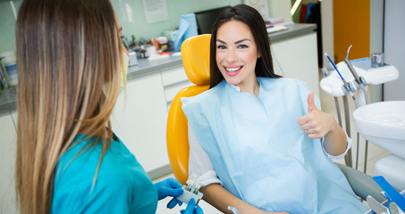 Young beautiful women in dentist chair, check and select the color of the teeth.