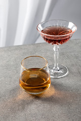 glass of cognac near red wine on white