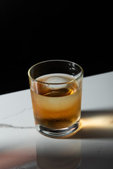 ice cube in glass of whiskey isolated on black
