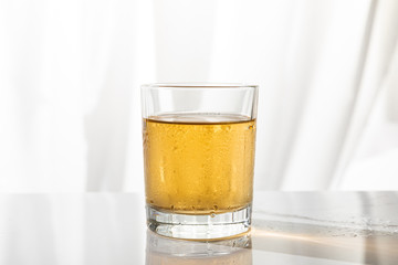 wet glass of strong whiskey on white with copy space