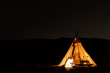 キャンプ場の夜に明かりが灯されたテント © lastpresent