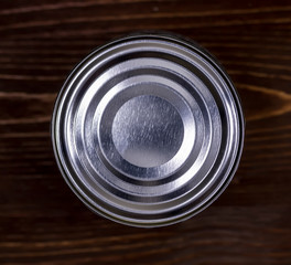 top view of a metal food can with copyspace isolated on a wooden background. Cover blank tin on wood table, canned meal , tinned goods
