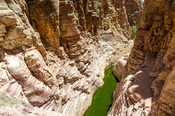 A spectacular canyon with a natural pool at the bottom and steep rock faces around it, hiking trail...