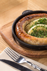 Home-made Pork Sausages in rustic pan. Sausages cooking in frying pan. Close up of fried sausages in frying pan over wooden background