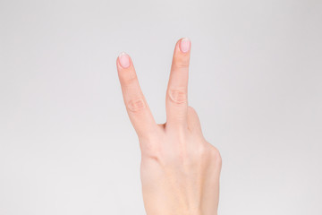Closeup view photography of white female hand with raised two fingers up.