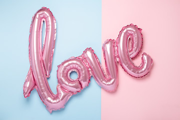 Pink balloons in the form of word Love on pink and blue background. Valentines day celebration.