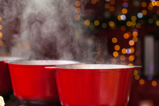 Street food. Hot mulled wine. Thick steam over cauldrons with hot wine. Outside. Close-up photo.