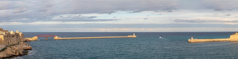 Old lighthouse and breakwater bridge of Fort Ricasoli from Valletta in Malta