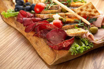 meat and cheese slices with fruits, vegetables, appetizer, prosciutto, sausages. Meat and cheese plate.Traditional italian antipasto, cutting board with salami, cold smoked meat, prosciutto, ham, chee