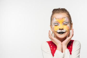 cute kid with tiger muzzle painting on face holding hands near face while standing with closed eyes isolated on white