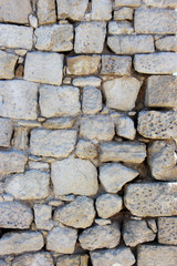 background of solid stone wall made of cement, limestone and light cobblestones with uneven surface