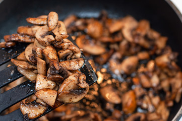 Juicy and mouth-watering champignons on the kitchen shoulder fried. Stir fried mushrooms during cooking.