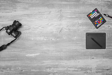 Biurko fotografa. Aparat, tablet piórkowy i wzornik koloru leżący na drewnianym biurku.