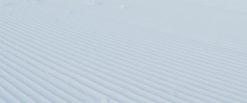 CU DOLLY SHOT of snowboarder riding on a fresh groomed perfect corduruy slope on a skiing resort. 4K UHD RAW graded footage