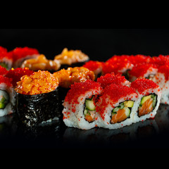 Japanese Sushi isolated on black background. Reflection in a mirror surface. Close up. Studio photo.