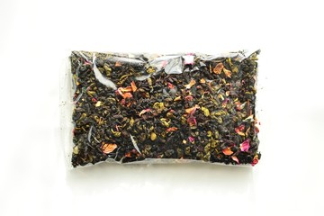 Black tea in a plastic transparent bag. Tea with flowers and packaging on a white background isolated. View from above.