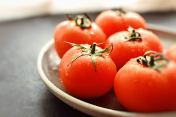 Juicy tomatoes in a gray clay plate. Tomatoes side view. Useful tasty vegetables for salad, ingredient. Place for text.