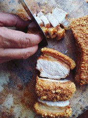 The man’s hand is cutting crispy pork belly on the cutting board, Crispy pork