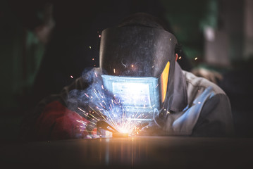 Welder is welding a metal frame close up. - Powered by Adobe