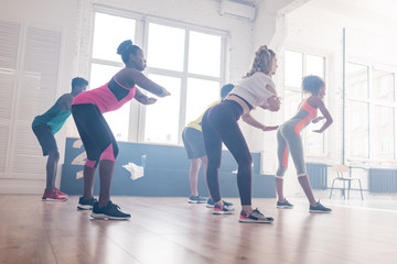 Side view of young multicultural dancers training zumba movements in dance studio