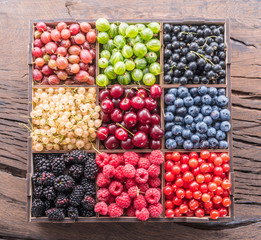 Colorful berries in wooden box on the table. Top view.