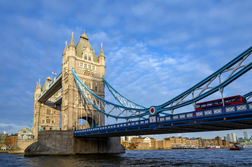 Obraz premium Tower Bridge in the City of London, UK with red London bus. Tower Bridge crosses the River Thames and is one of the most famous tourist sights in London. View of Tower Bridge in late afternoon light.