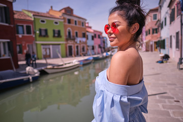 traveler woman posing among colorful houses on Burano island, Venice. Tourism in Italy concept