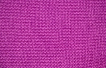 Pink wool yarn of knitted texture. Hand knitting. Close up. Pink background.