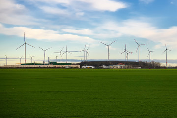 Fototapeta na wymiar Wind power generators on a green field against a background of blue sky.