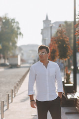 young stylish guy in a shirt walking down a European street on a sunny day