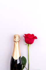 A bottle of champagne and a red rose on a pink background