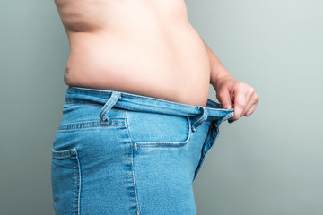 Full female body in jeans. Large postpartum belly. The concept of losing weight by summer. 