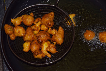 gram flour fritters, boiling oil in frying pan with dark background