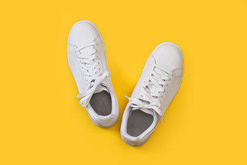 Zapatillas blanca sobre fondo amarillo liso brillante. Vista superior. Copy space