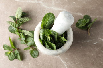 Mortar, pestle and mint on grey background, top view