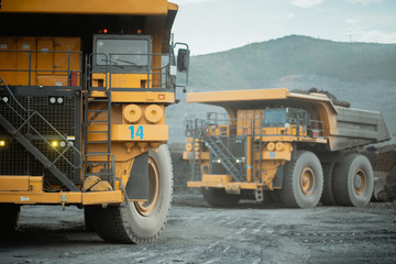 Two mining dump trucks are working at the gold mine site.
