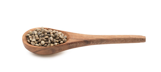 Brown wooden spoon with hemp seeds seen from the side and isolated on white background