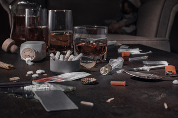 Various drugs, alcohol and cigarettes are on the wooden table. Substances that cause drug and alcohol dependence. Low key.