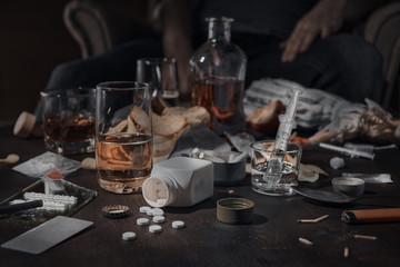 Various drugs, alcohol and cigarettes are on the wooden table. Substances that cause drug and alcohol dependence. Low key.