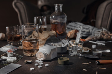 Various drugs, alcohol and cigarettes are on the wooden table. Substances that cause drug and alcohol dependence. Low key.