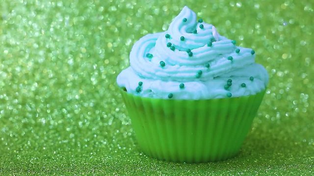 Cupcake with green blue cream and on a green background with bokeh. Concept holiday food dessert. Selective focus.