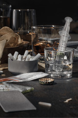 Various drugs, alcohol and cigarettes are on the wooden table. Substances that cause drug and alcohol dependence. Low key.