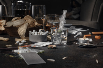Various drugs, alcohol and cigarettes are on the wooden table. Substances that cause drug and alcohol dependence. Low key.