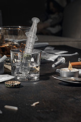 Various drugs, alcohol and cigarettes are on the wooden table. Substances that cause drug and alcohol dependence. Low key.