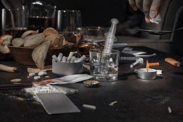 Various drugs, alcohol and cigarettes are on the wooden table. Substances that cause drug and alcohol dependence. Low key.