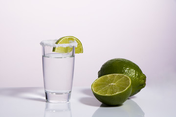 Silver tequila in a glass with salt and lime on a white isolated background. Alcoholic beverages....
