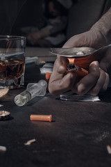Various drugs, alcohol and cigarettes are on the wooden table. Substances that cause drug and alcohol dependence. Low key.