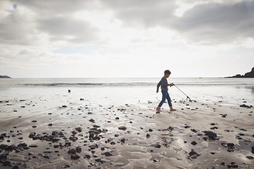 Young Boy Collecting Litter On Winter Beach Clean Up