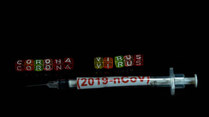 Colorful text "Corona virus" and   syringe have red text "(2019-nCoV)  put on  Black background. corona virus Concept.
